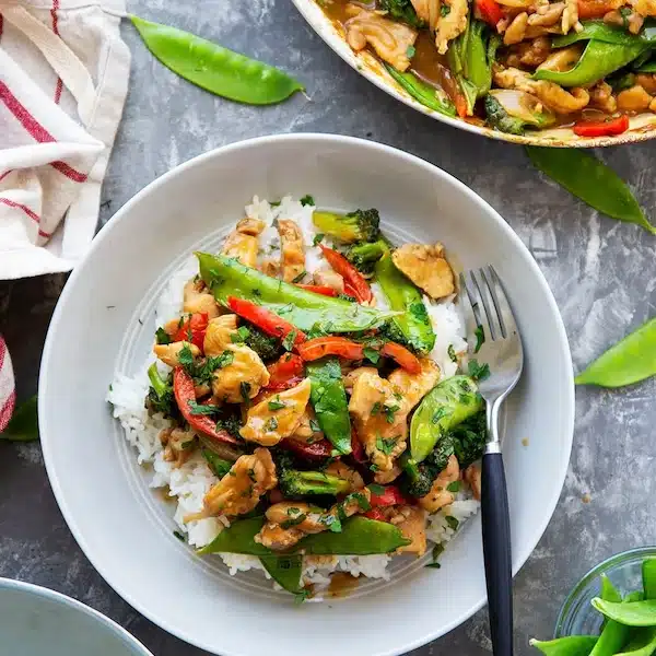 Sauté de poulet avec du riz et des légumes dans une assiette avec une fourchette