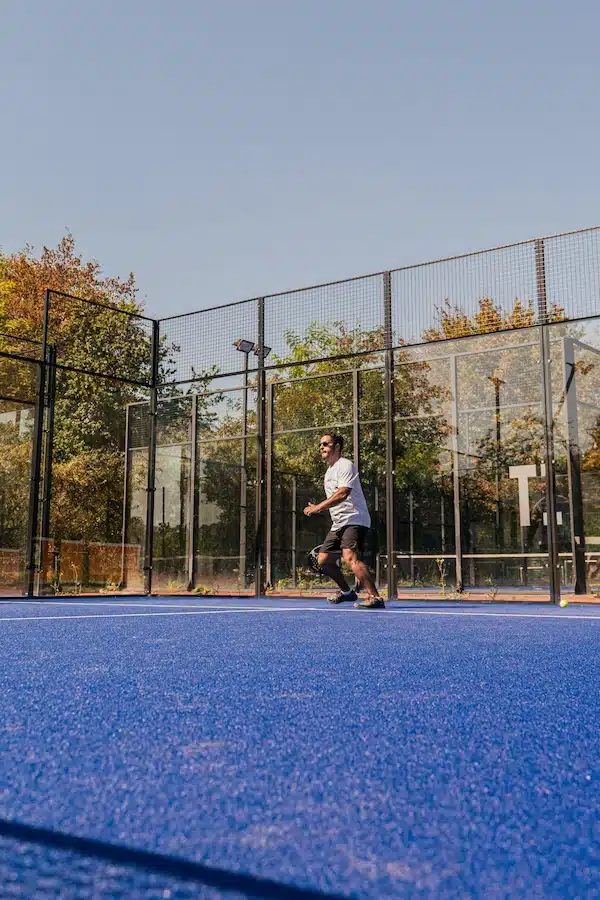 Joueur de padel en action en fond de terrain près des vitres