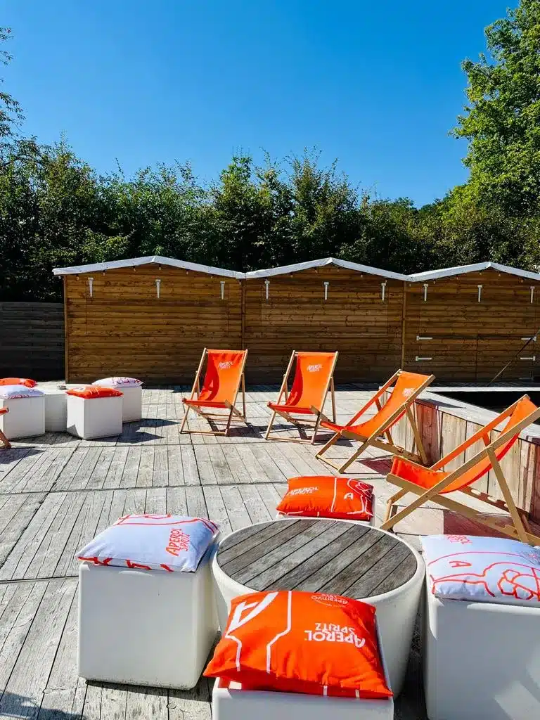 Terrasse en bois avec des chaises longues et des coussins de la marque Aperol